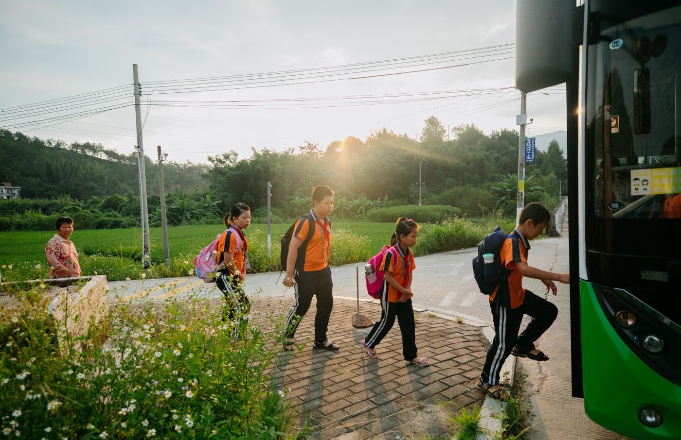 Grupo de estudiantes con mochilas abordando el bus escolar al amanecer